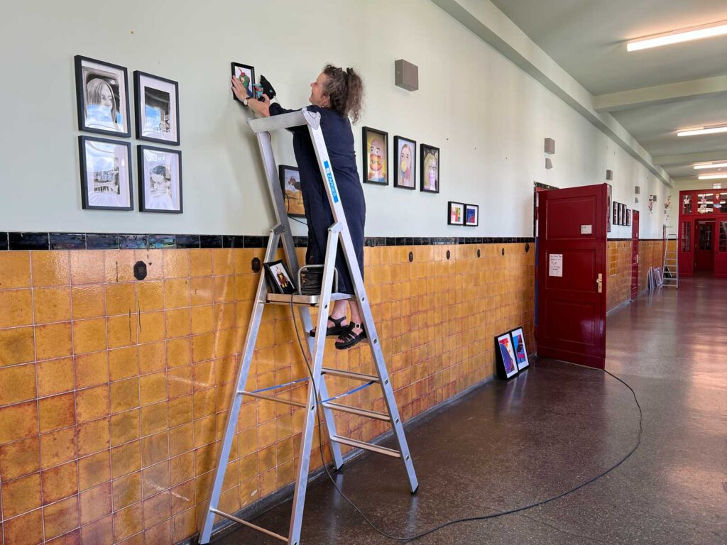 Frau Kuhn hängt die neuen Bilder für die Galerie des Rückert-Gymnasiums in den Fluren der Schule auf.